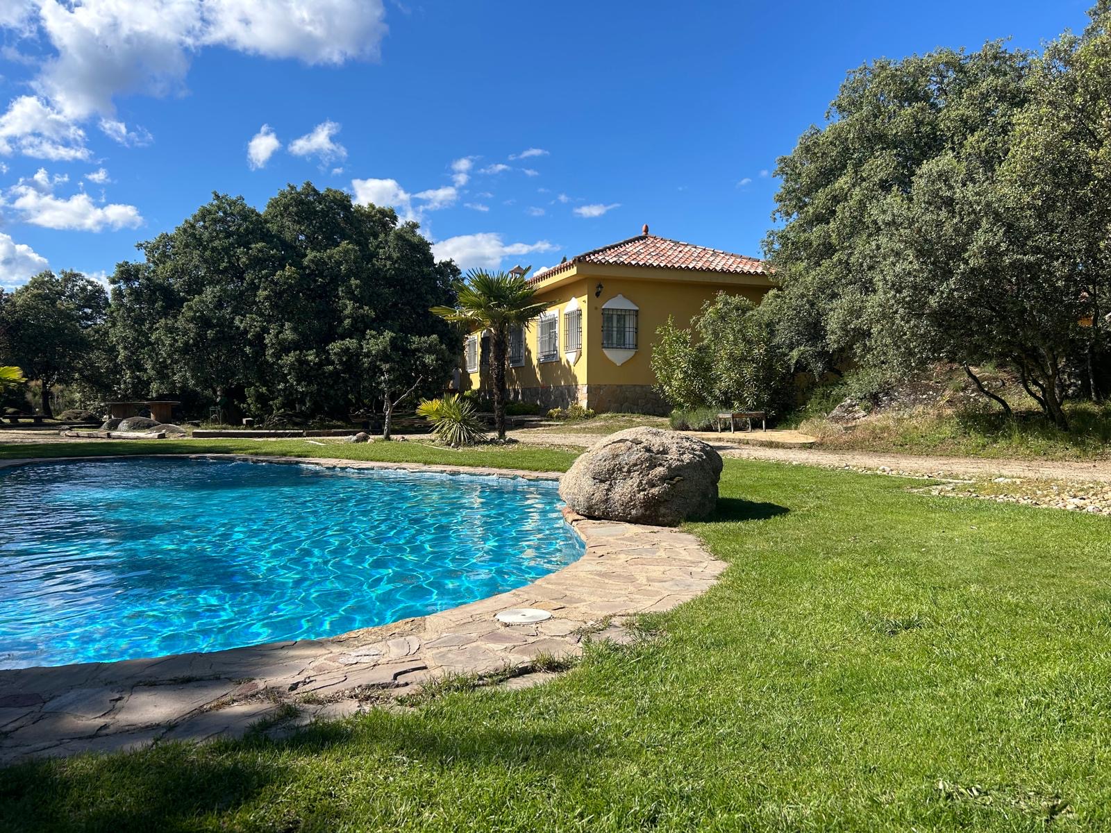 Piscina y fachada colonial entre encinas